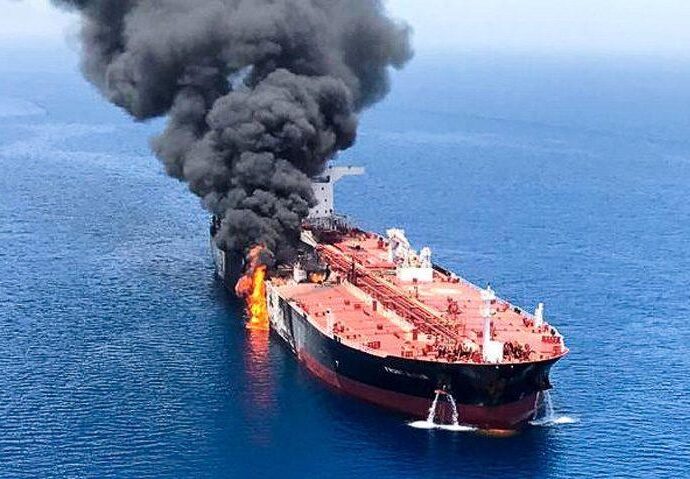 a small boat in a body of water with smoke coming out of it: An oil tanker is seen after it was attacked at the Gulf of Oman, June 13, 2019.