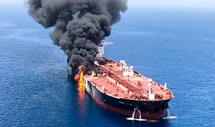 a small boat in a body of water with smoke coming out of it: An oil tanker is seen after it was attacked at the Gulf of Oman, June 13, 2019.