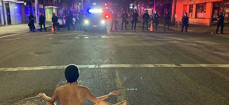 A protester dubbed 'Naked Athena' confronted Portland police wearing only a face mask and beanie