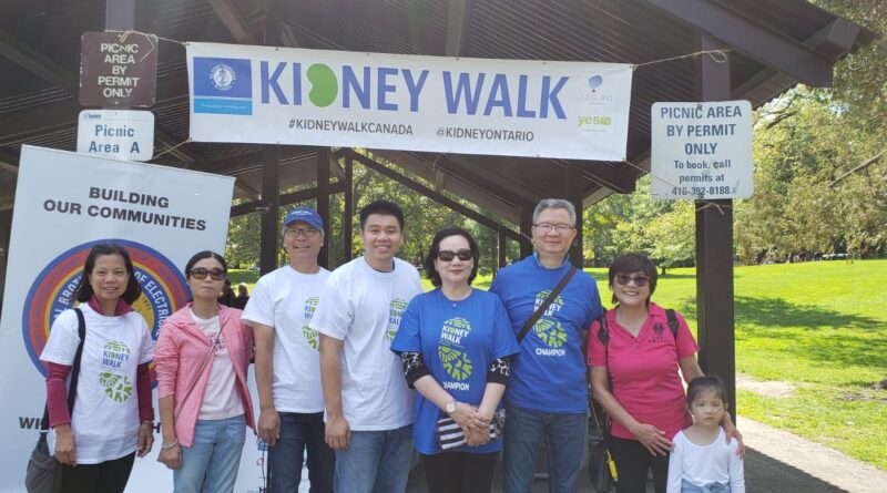 A group of people standing in front of a sign Description automatically generated