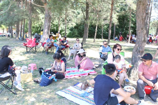 A group of people sitting on the grass Description automatically generated with low confidence