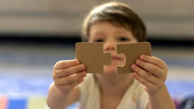 Child holds two puzzle pieces that will fit together.