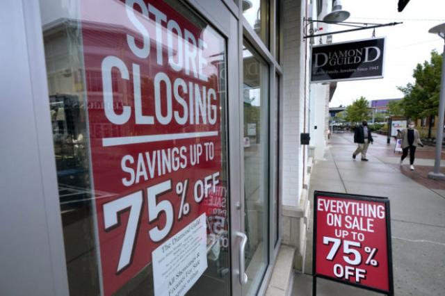 In this Sept. 2, 2020 photo, aassers-by walk past a business storefront with store closing and sale signs in Dedham, Mass.  The coronavirus and the drastic measures put in place by government officials to try to control its spread had a severe toll on many small businesses in the U.S.  (AP Photo/Steven Senne)