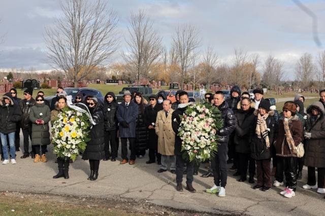 A group of people standing together holding flowers Description automatically generated