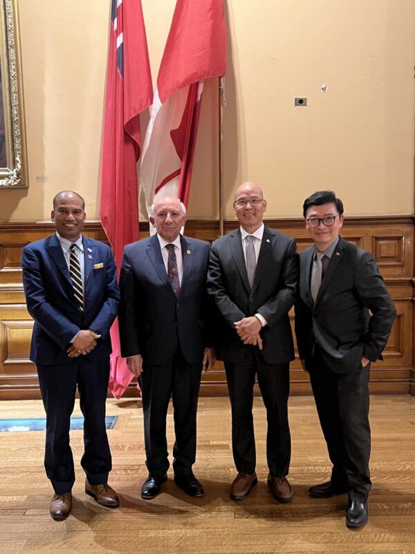 A group of men in suits standing in front of a flag Description automatically generated