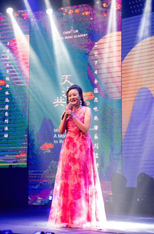 A person in a pink dress holding a microphone Description automatically generated