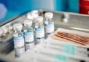 covid vaccine vials, syringes, and bandaids on a metal tray