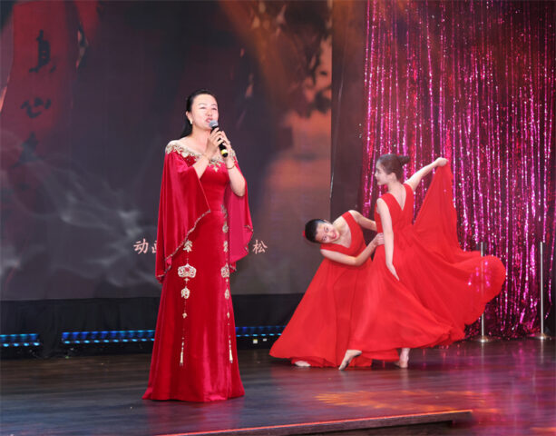 A person in red dress on stage with a microphone AI-generated content may be incorrect.